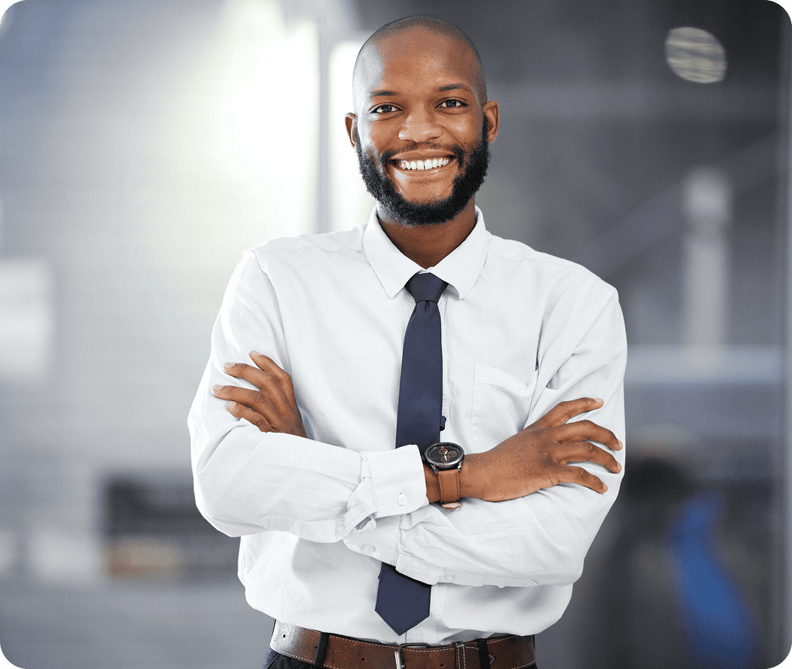 Confident businessman smiling with arms crossed in a modern office.