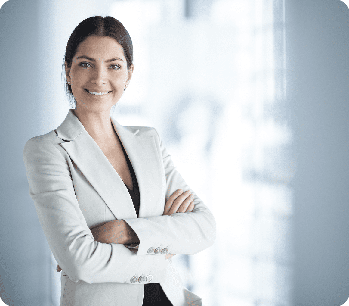 Confident businesswoman in a light blazer smiling with arms crossed.