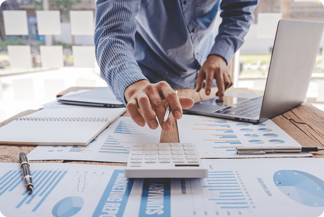 Person using calculator and laptop for financial analysis.